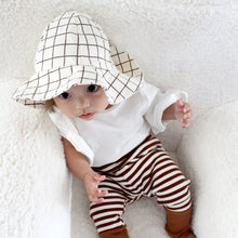 Load image into Gallery viewer, Baby sitting wearing white and brown grid cotton bucket hat, white flutter sleeve shirt and brown and white striped cotton leggings