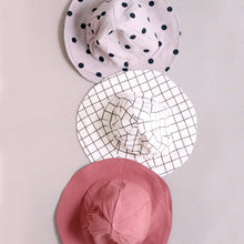Load image into Gallery viewer, Three baby cotton bucket hats. Brown and white grid pattern, solid red, and beige with black polka dots.