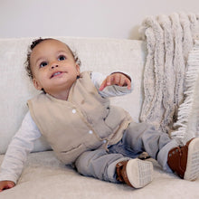 Load image into Gallery viewer, Baby sitting on couch wearing white long sleeved shirt with beige padded vest and grey pants and brown boots