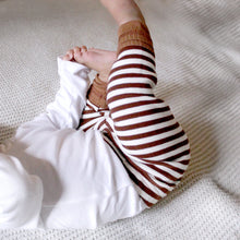 Load image into Gallery viewer, A baby from the neck down laying on their back. Baby has legs in the air and is wearing a white long sleeved shirt with brown and white striped leggings with a brown ribbed cuff at the bottom.