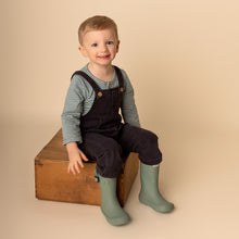 Load image into Gallery viewer, toddler sitting on brown wooden block wearing green striped long sleeved shirt, dark denim overalls and green rain boots