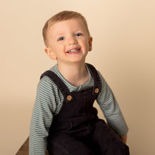 Load image into Gallery viewer, toddler sitting smiling at camera wearing green long sleeved shirt with dark denim jumpsuit