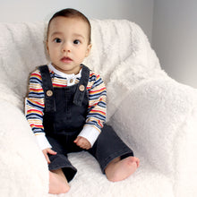 Load image into Gallery viewer, baby sitting on white chair wearing multicolored long sleeved shirt with dark denim jumpsuit