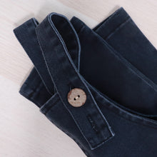 Load image into Gallery viewer, baby blue denim overalls folded with the adjustable strap and button showing