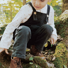 Load image into Gallery viewer, toddler kneeling wearing blue denim overalls, white long sleeved shirt and brown boots