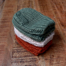Load image into Gallery viewer, baby hand knit mittens stacked on top of each other on brown background