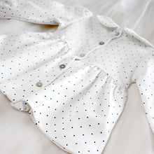 Load image into Gallery viewer, back of white baby tunic with navy blue polka dots and peter pan collar featuring mother of pearl buttons