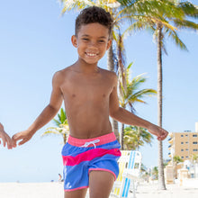 Load image into Gallery viewer, toddler standing on beach wearing pink and blue striped swim trunks