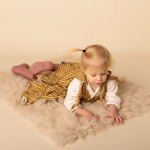 Load image into Gallery viewer, baby laying wearing white long sleeved shirt and yellow gold gingham strapless tiered dress and pink rainboots