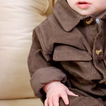 Load image into Gallery viewer, Baby sitting wearing brown corduroy jumpsuit 
