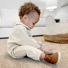 Load image into Gallery viewer, Baby sitting on the carpeted floor playing with cups wearing white corduroy jumpsuit and brown boots 

