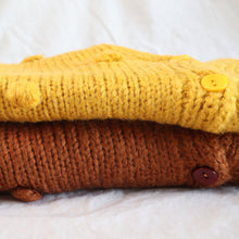 Load image into Gallery viewer, Baby knit yellow and brown pom pom cardigans folded sitting on top of each other
