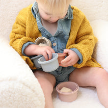 Load image into Gallery viewer, Baby sitting on a chair holding cups wearing denim cotton romper and yellow knit pom pom cardigan
