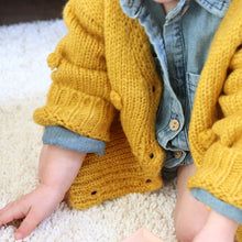 Load image into Gallery viewer, Baby sitting wearing denim cotton romper and yellow pom pom cardigan with buttons

