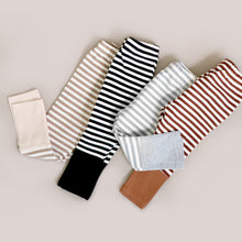 Load image into Gallery viewer, four pairs of striped cotton baby leggings laying folded vertically together.  from left to right, tan, black, light grey and brown. 
