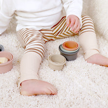 Load image into Gallery viewer, baby sitting wearing a white long sleeve and tan and white striped cotton baby leggings with tan cuff at bottom. 
