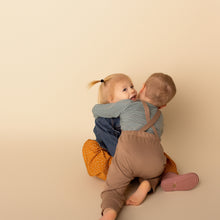 Load image into Gallery viewer, toddler kissing another toddler on ground wearing green long sleeved henley and brown cotton jumpsuit
