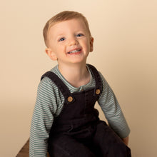 Load image into Gallery viewer, toddler sitting smiling at camera wearing green long sleeved shirt with dark denim jumpsuit
