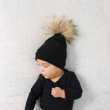 Load image into Gallery viewer, Baby laying wearing black long sleeve shirt and black beanie with fur pom pom topper
