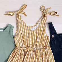 Load image into Gallery viewer, gingham gold strapless baby dress laying next to green romper and dark denim baby romper

