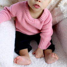 Load image into Gallery viewer, baby sitting wearing pink crew neck sweater and dark denim overalls 

