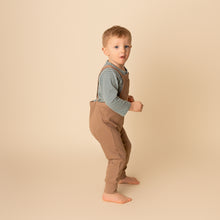 Load image into Gallery viewer, toddler standing wearing green long sleeved striped shirt and brown overalls
